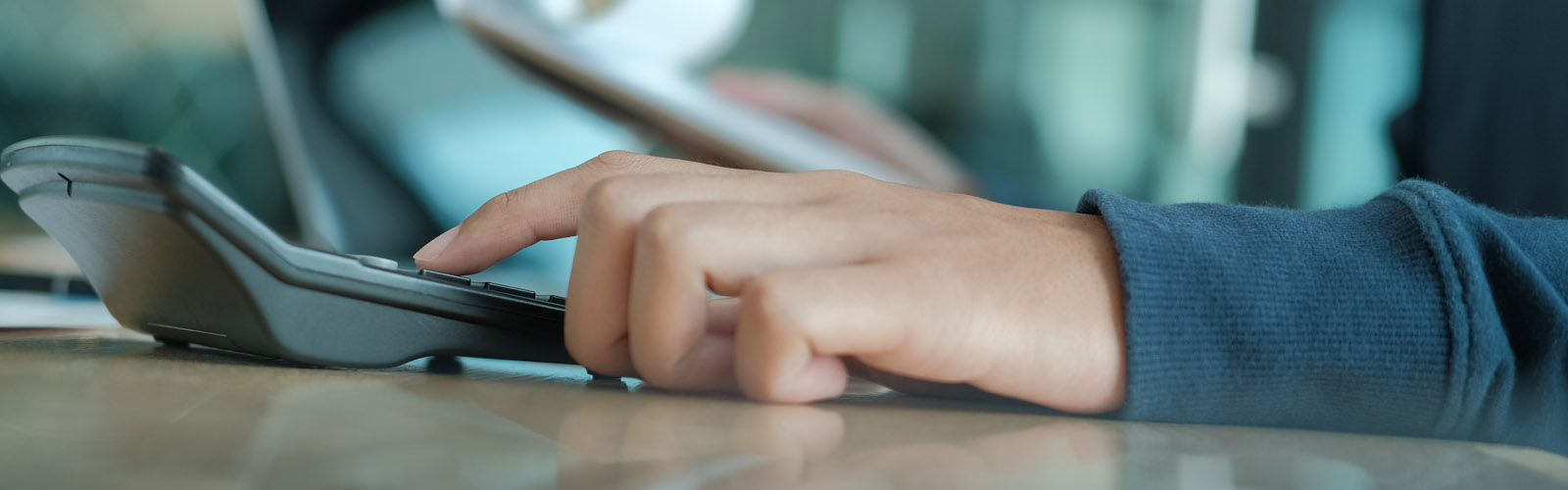 mans hand using calculator - payrolling benefits_web_1600x500.jpg