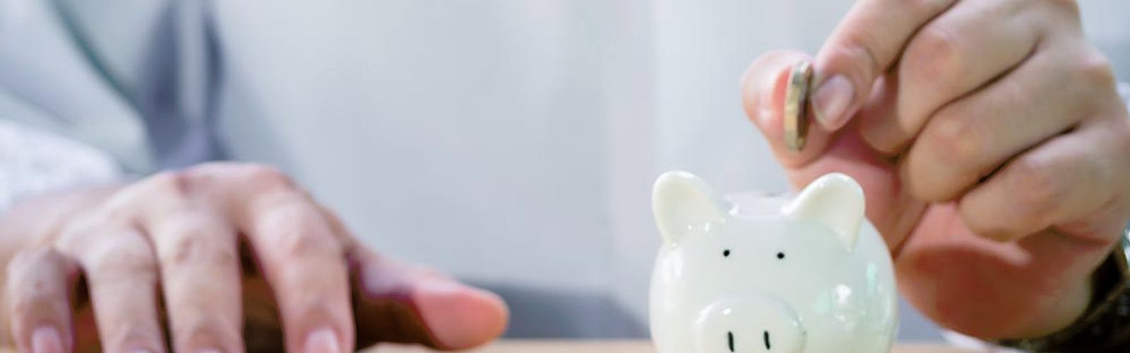 hand puttin coin into piggy bank pensions - web.jpg