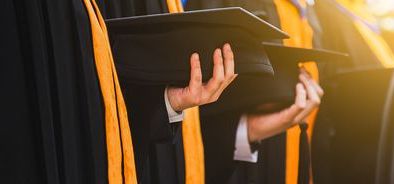 graduates holding mortarboards with bright sun 1600x500px.jpg